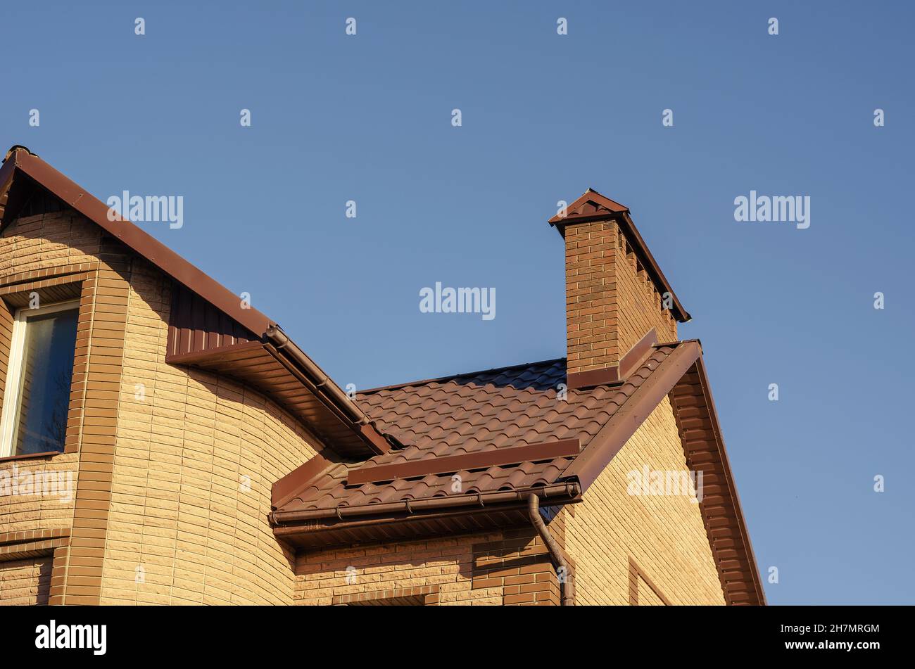 The brown roof with mantel chimney of a beautiful modern stone mansion ...