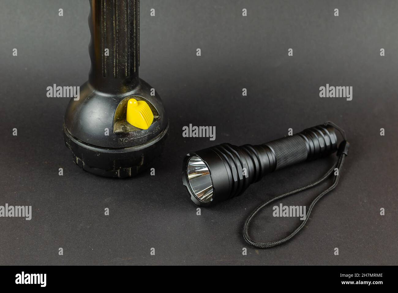Small Modern tactical and large obsolete flashlights on gray background. Selective Focus. Stock Photo