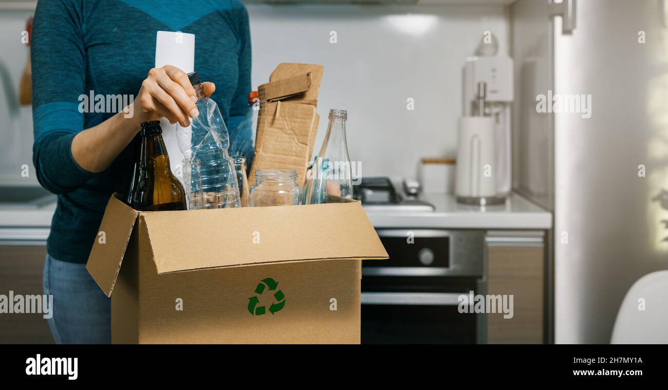 household waste sorting - woman inserting plastic bottle in recycling garbage box at home. copy space Stock Photo