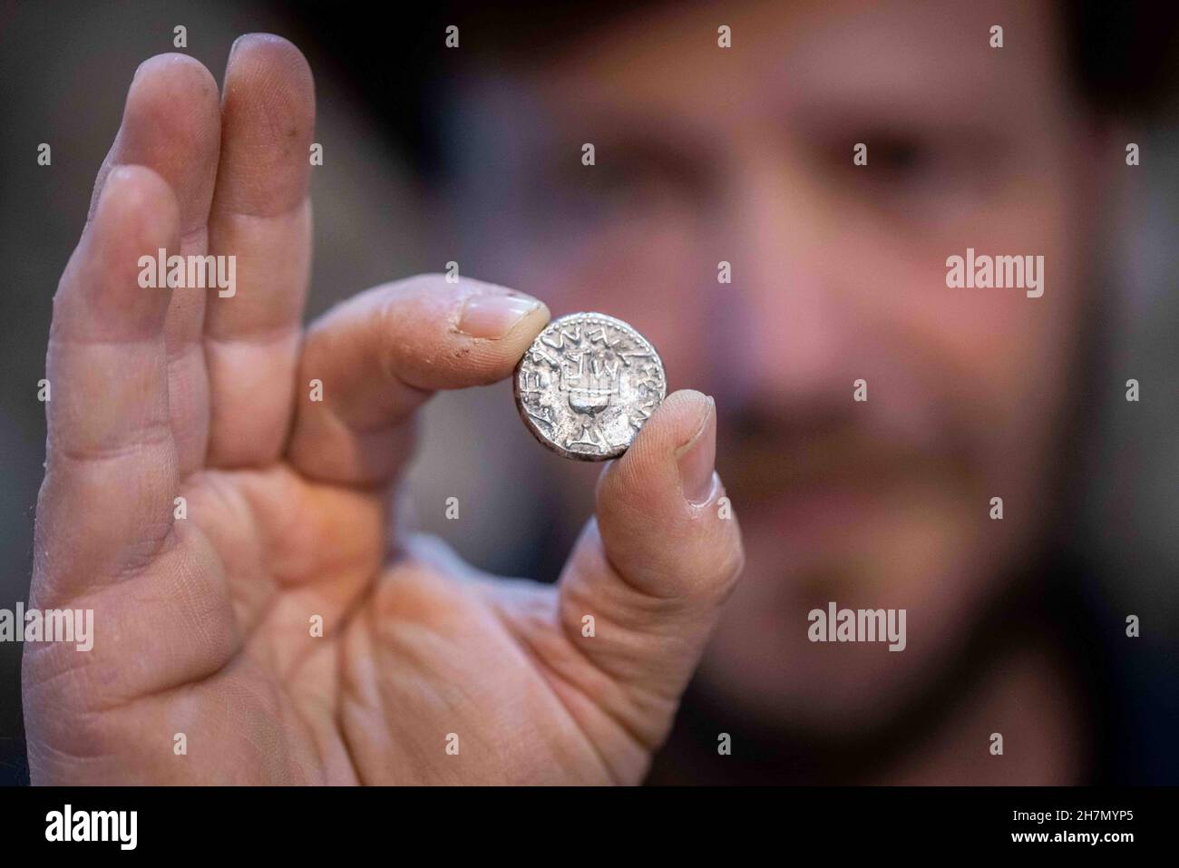 (211124) -- JERUSALEM, Nov. 24, 2021 (Xinhua) -- An archaeologist shows the ancient silver coin dating back to about 2,000 years ago in Jerusalem, Nov. 23, 2021. An ancient shekel, dating back to about 2,000 years ago, was discovered in Jerusalem, the Israel Antiquities Authority (IAA) said on Tuesday. The shekel, which weighs about 14 grams, was probably minted by one priest of the Jewish Second Temple, shortly before the destruction of the temple. (JINI via Xinhua) Stock Photo