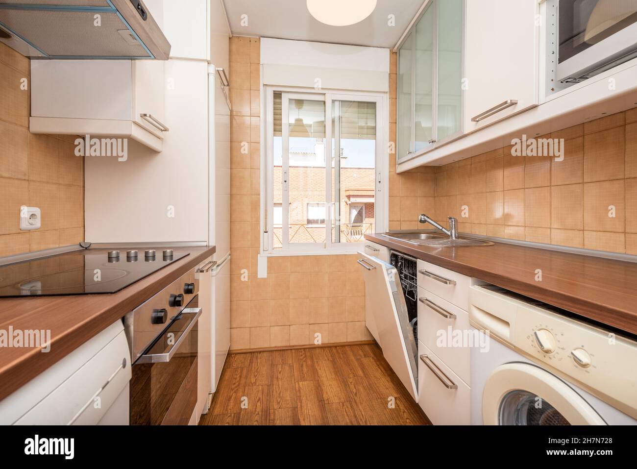 Kitchen with woodcolored countertop, open dishwasher, ceramic hob