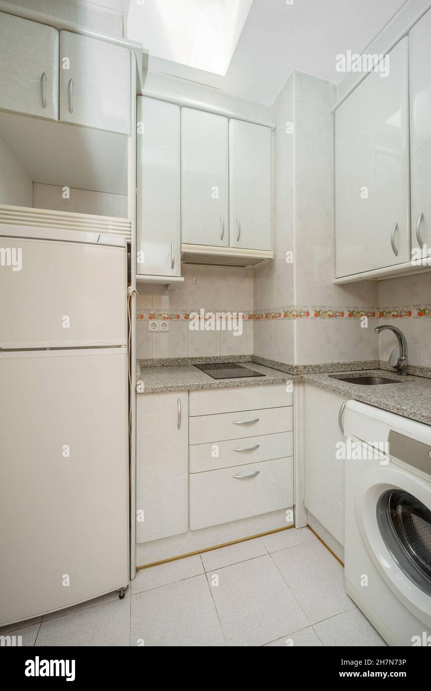 Small kitchen with gray granite countertop with ceramic hob, fridge and