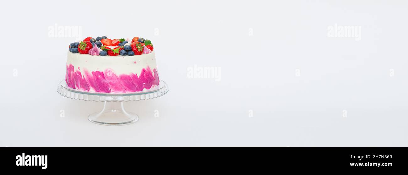 Delicate cake decorated with fresh berries strawberries blueberries white plain background. Festive dessert with berries Stock Photo