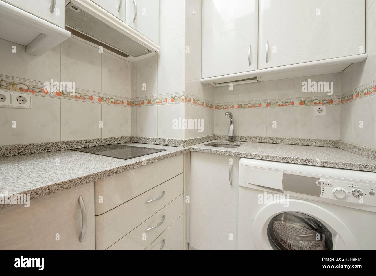 Small kitchen with gray granite countertop with ceramic hob, fridge and
