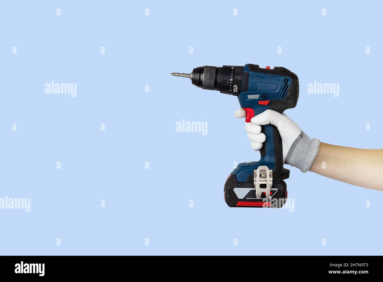 Gloved hands holding screwdriver, drill construction tools. Work tools on blue background Stock Photo
