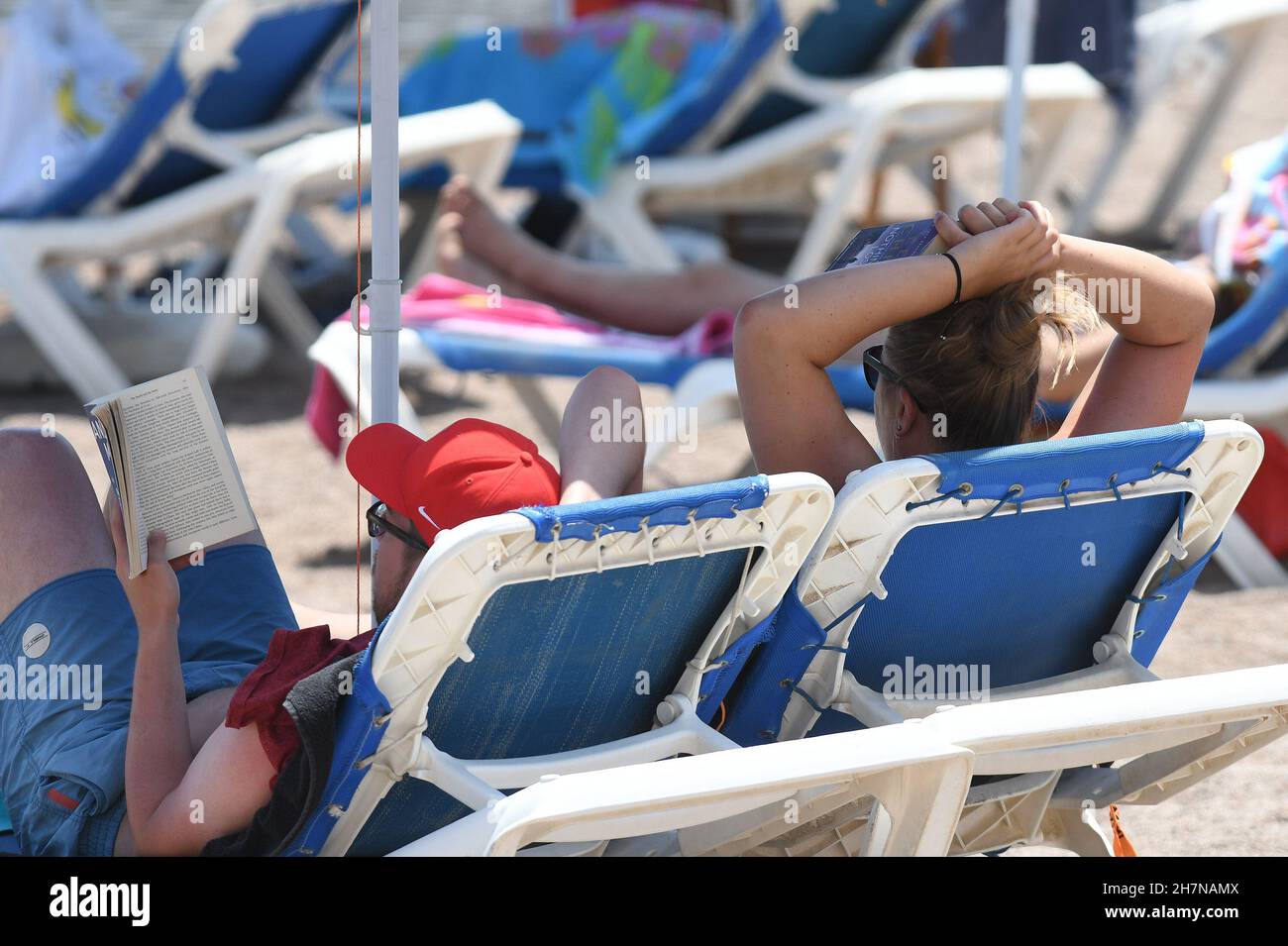 A lady sunbathes on a deckchair in Mellieha bay Malta Stock Photo Alamy