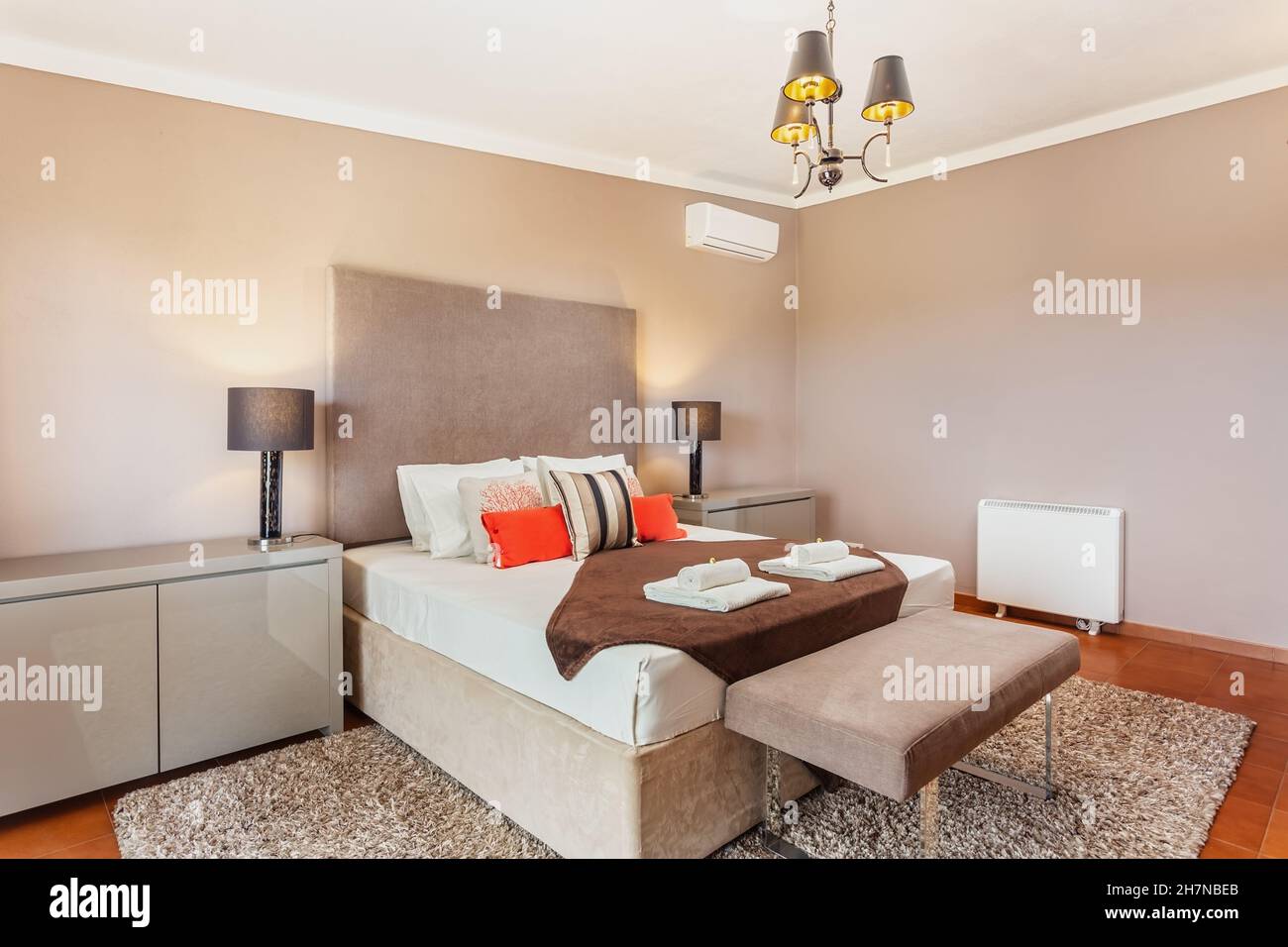 Modern bedroom with a large wide double bed for a couple. Blanket and