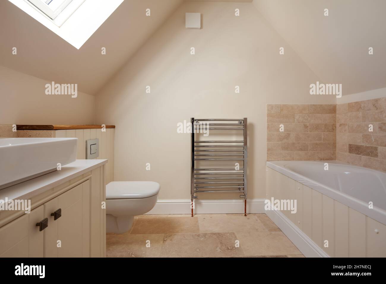Generic Modern bathroom suite in traditional style in vacant new home with panelled bath, sink, toilet and partially tiled walls. Stock Photo