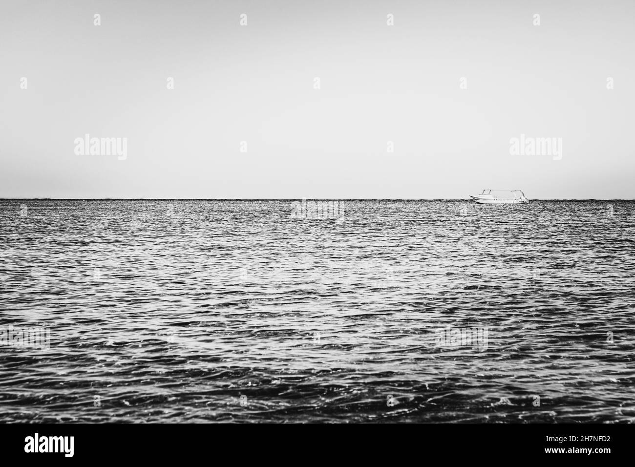 Black-white photography. Alone white boat or ship in silent sea or ocean water Stock Photo