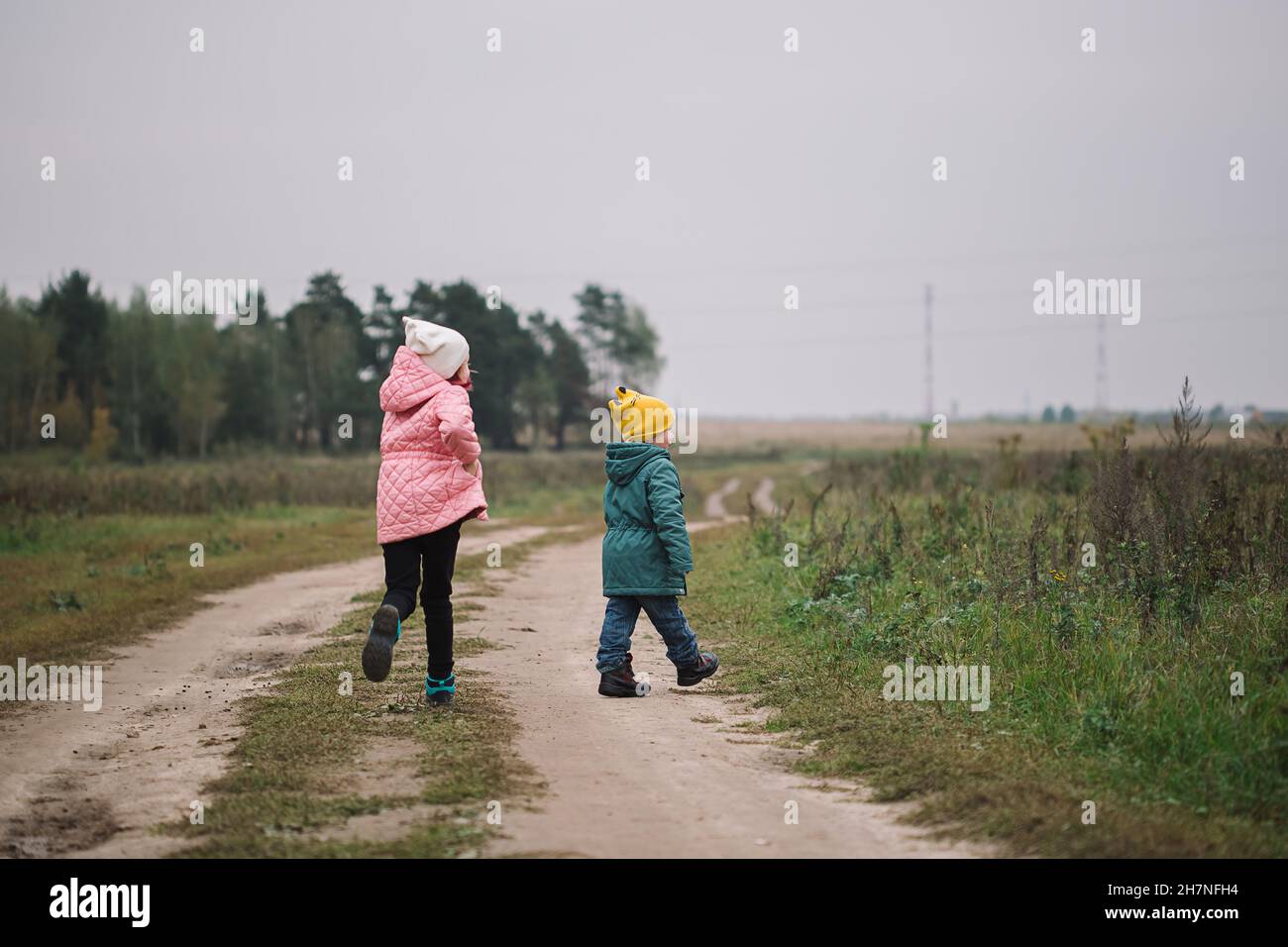 Children run into the field. Children play in the field running from flying drone Stock Photo