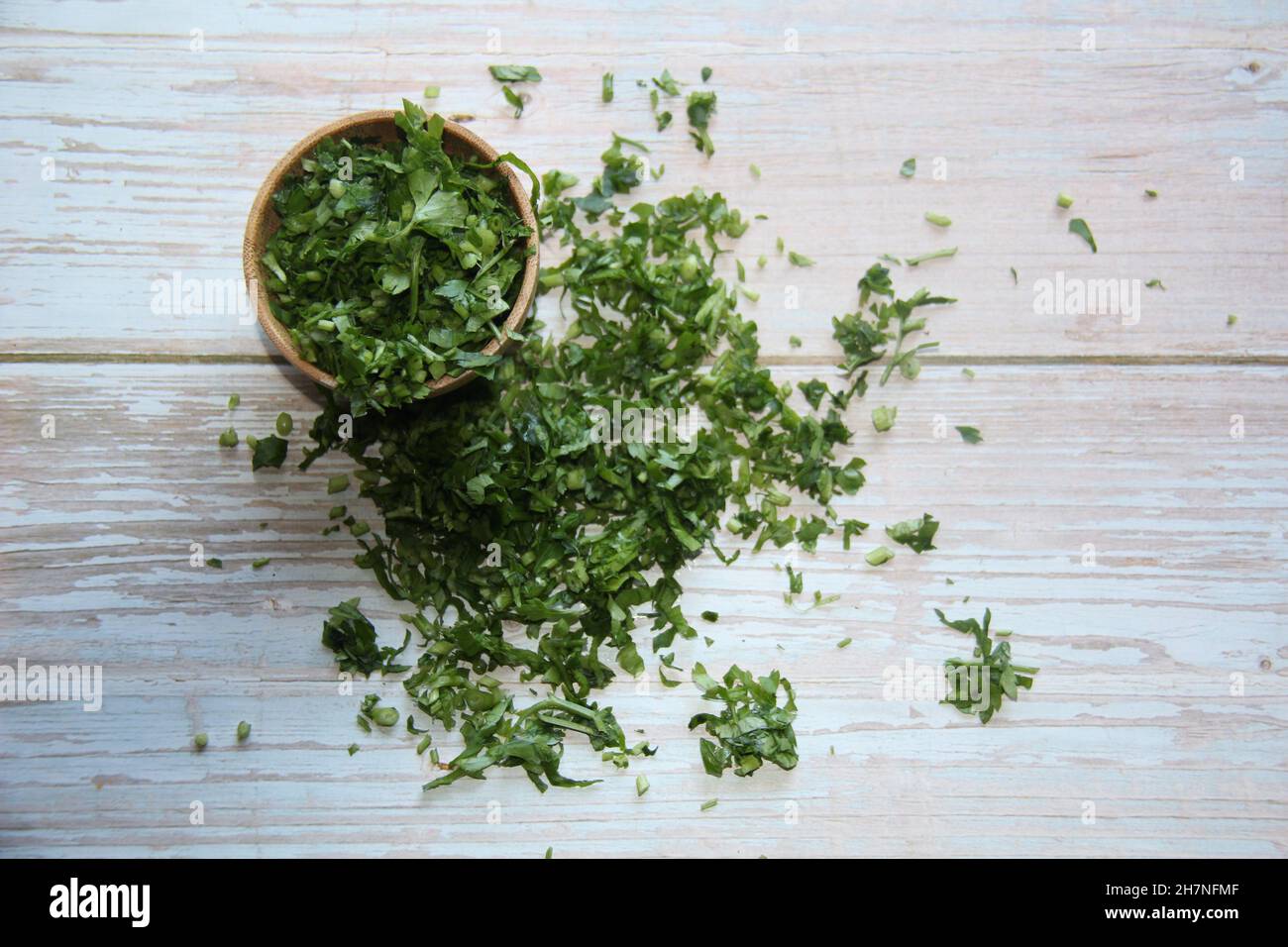 Parsley: fresh, chopped in a wooden bowl on an old wooden table. View from above. Stock Photo