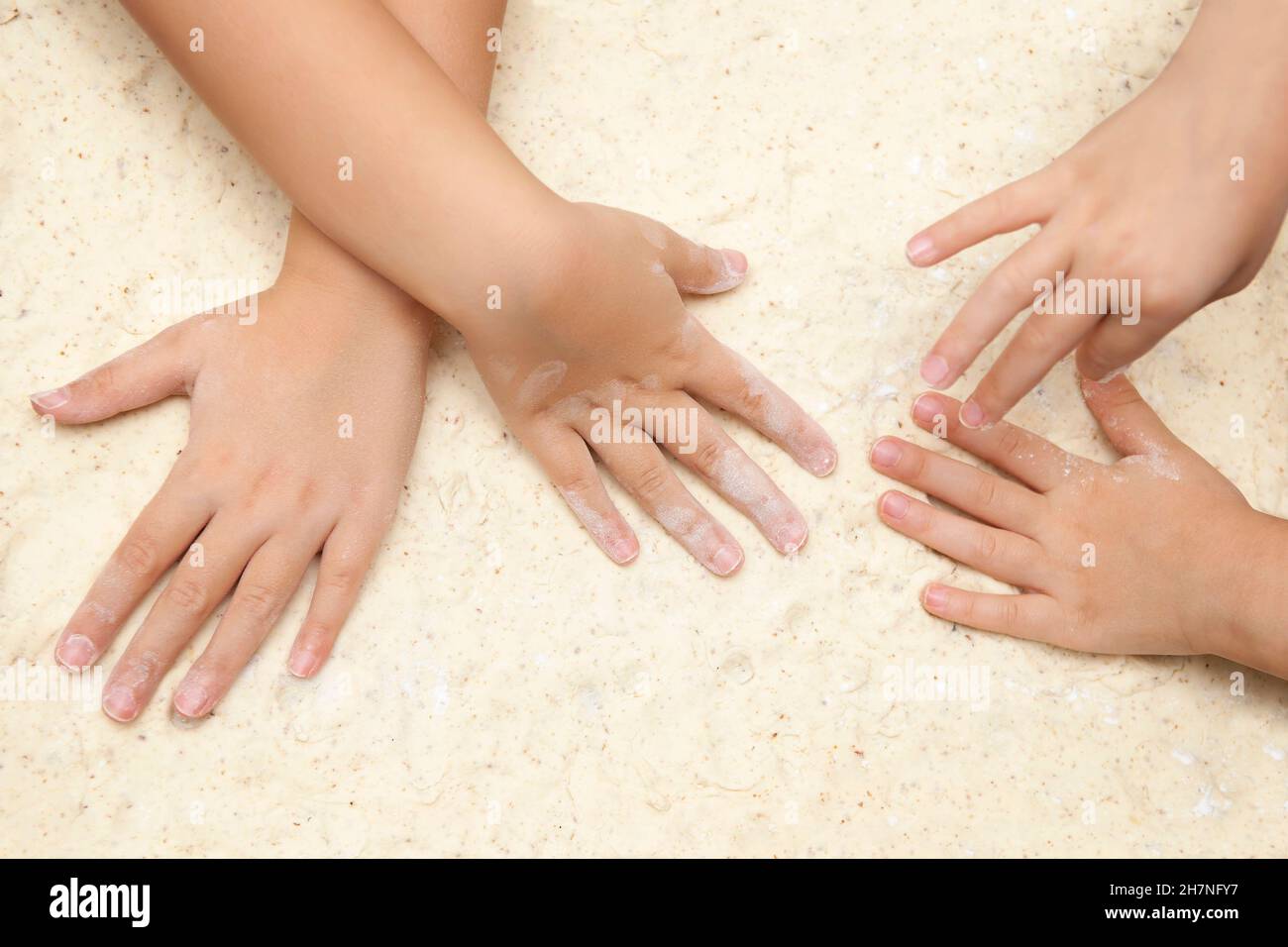 Children's hands preparing the dough for baking on the table. Shallow depth of field. SDF. Stock Photo