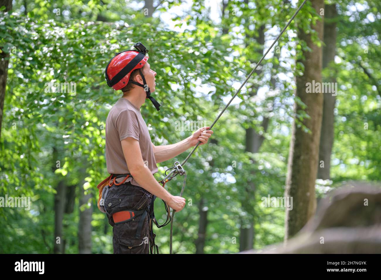 Man belays his partner climber with belaying device and rope. Climber's handsman holding