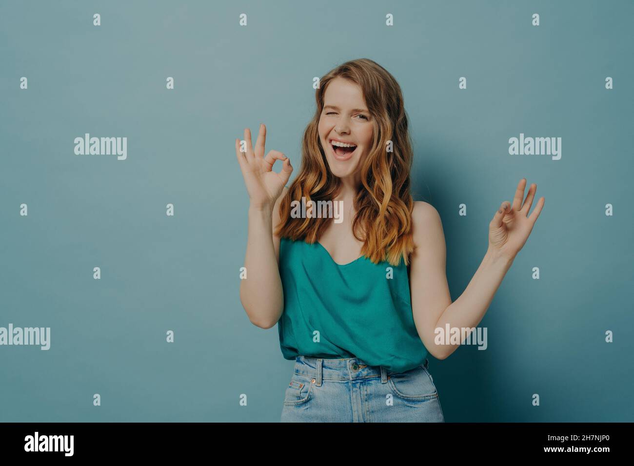 Charming funny girl shows OK sign with hands, winking and looking at camera with big smile Stock Photo