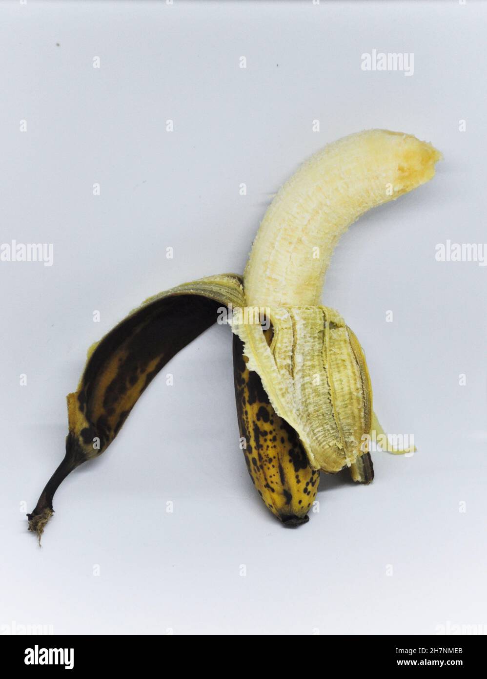 Cut out image of an over ripe banana which is half peeled set against a white background Stock Photo
