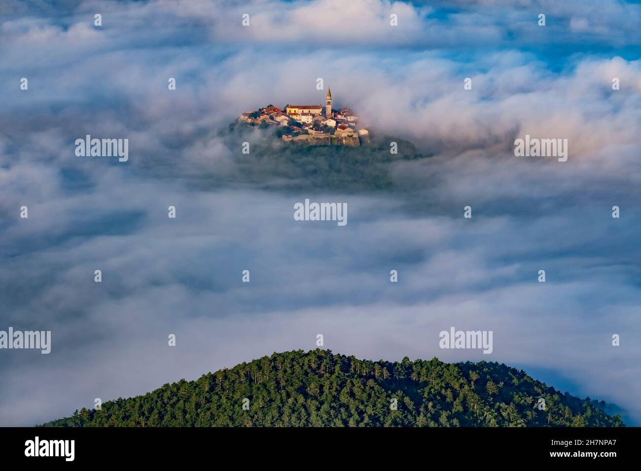 Ancient town Buzet with bell tower and old buildings flying above clouds. Unusual landscape of tourist destination in Istria, Croatia Stock Photo