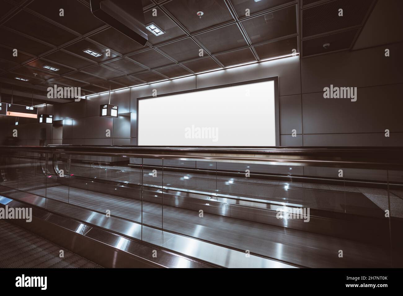 A big rectangular glowing blank neon billboard template near two travelators of a modern dark airport terminal; a mockup of an empty white banner indo Stock Photo