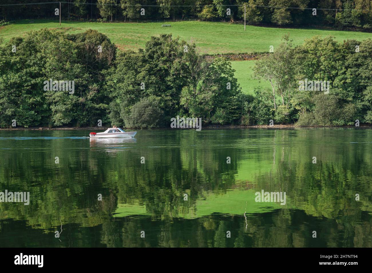Boat holiday, view in early summer of a couple cruising Lake Windermere in a small pleasure boat