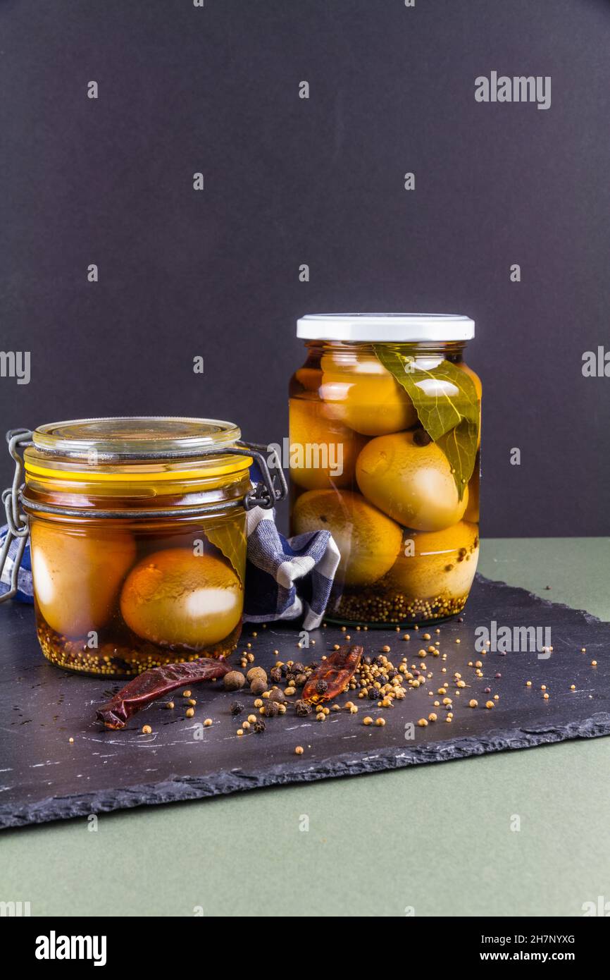 Two jars of eggs pickled in dark malt vinegar, portrait with copyspace
