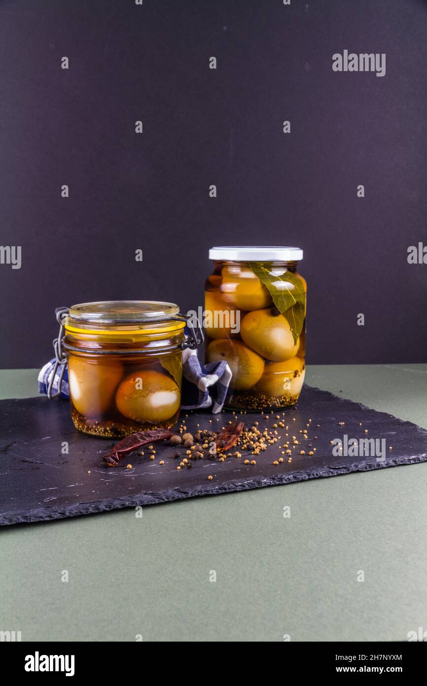 Two jars of eggs pickled in dark malt vinegar, portrait with copyspace
