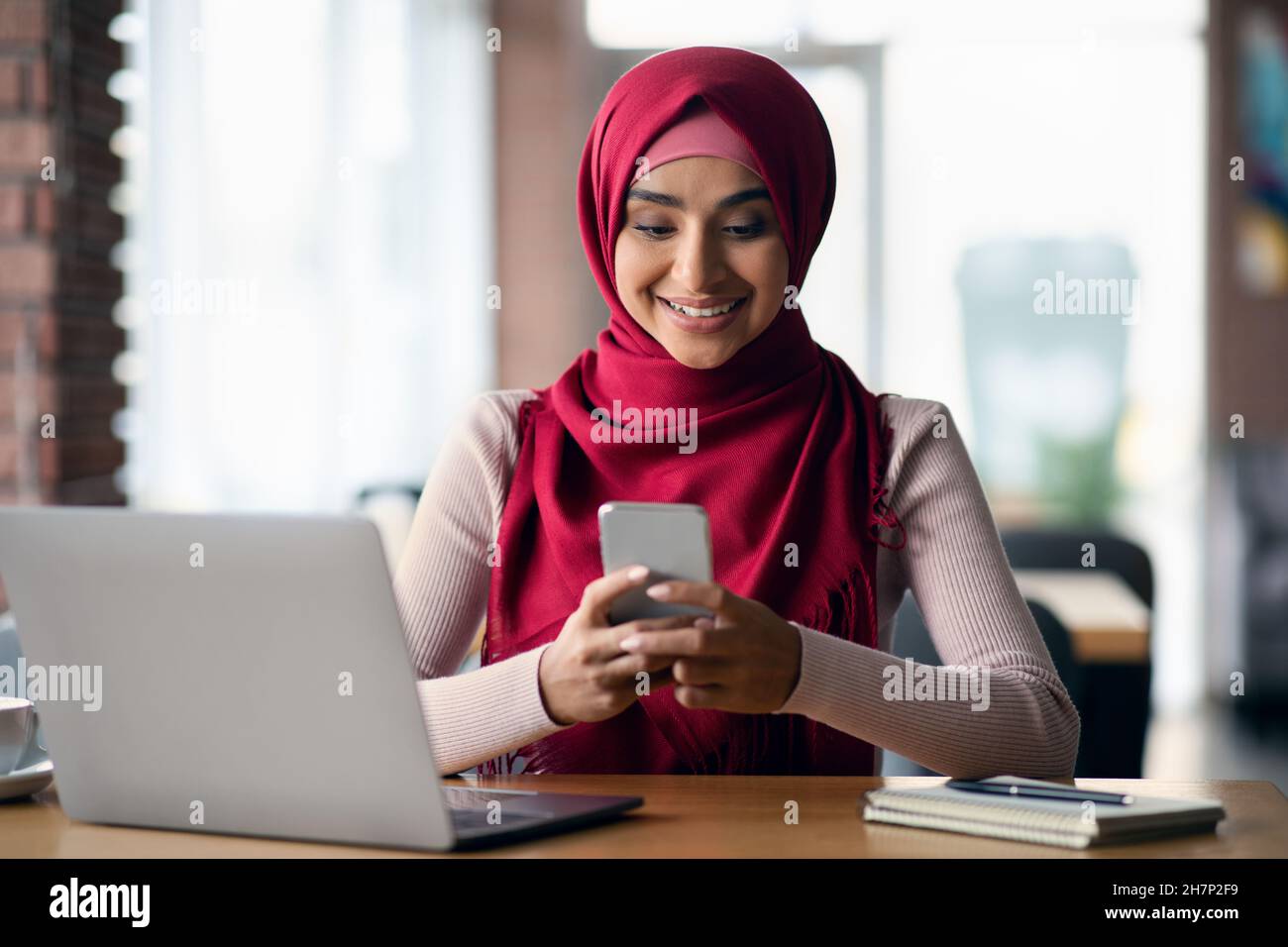 Happy muslim woman freelancer using laptop and smartphone Stock Photo ...