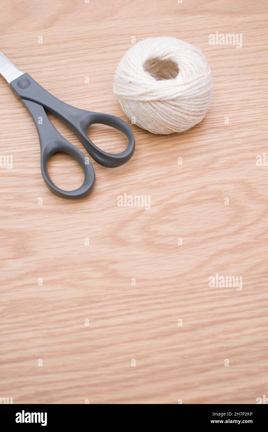 decorative rustic yarn ball and scissors on a wooden tabletop with copy ...