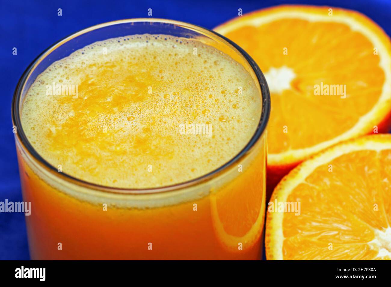Pretty freshly squeezed orange juice in glass and orange halves Stock Photo
