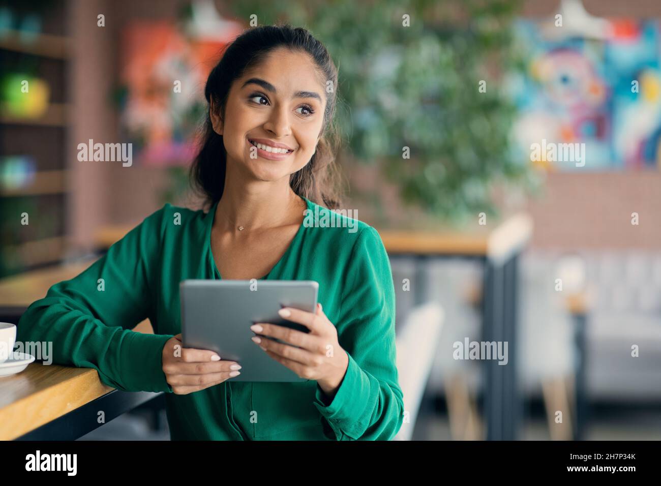 Attractive middle eastern woman having break at cafe, using pad Stock Photo