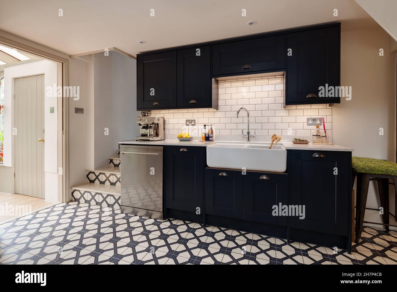 Great Wratting, Suffolk - August 21 2019: Cottage kitchen with distinctive traditional tile floor and striking black coloured cabinetry incorporating Stock Photo