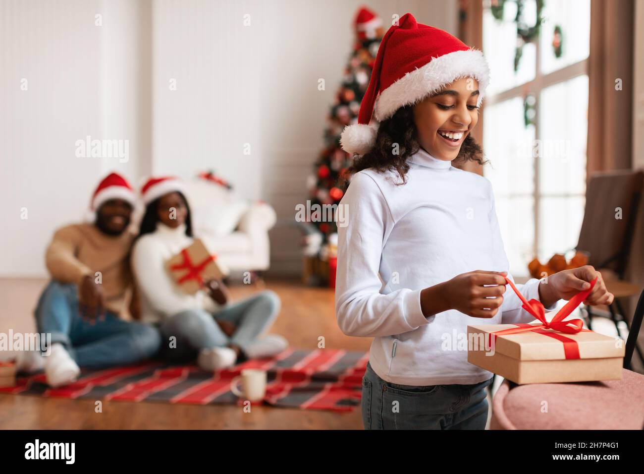 Happy black girl celebrating Christmas unwrapping gift box Stock Photo