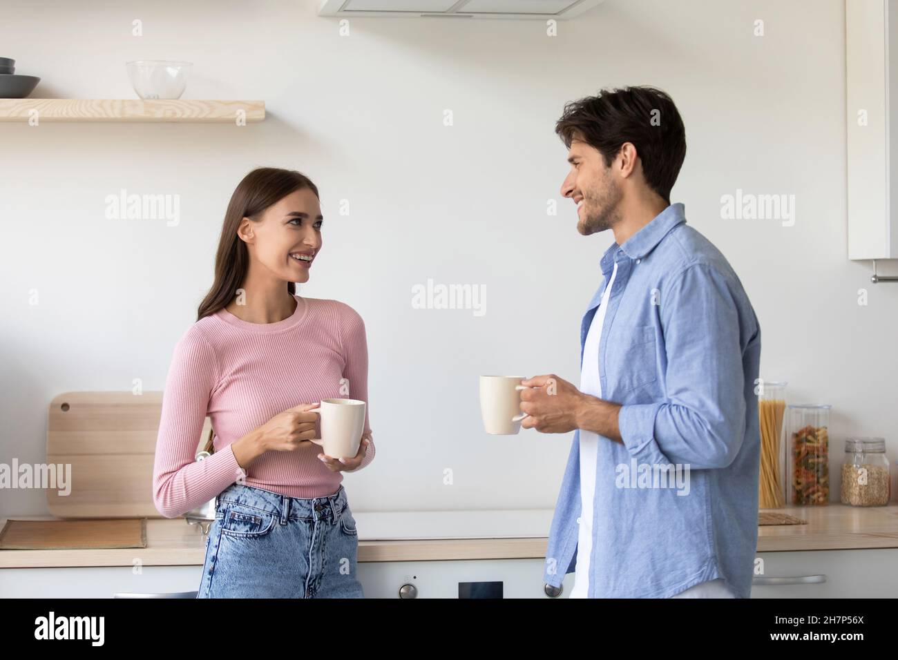 Cheerful millennial european lady and man with cups, communicating and drink coffee in morning Stock Photo