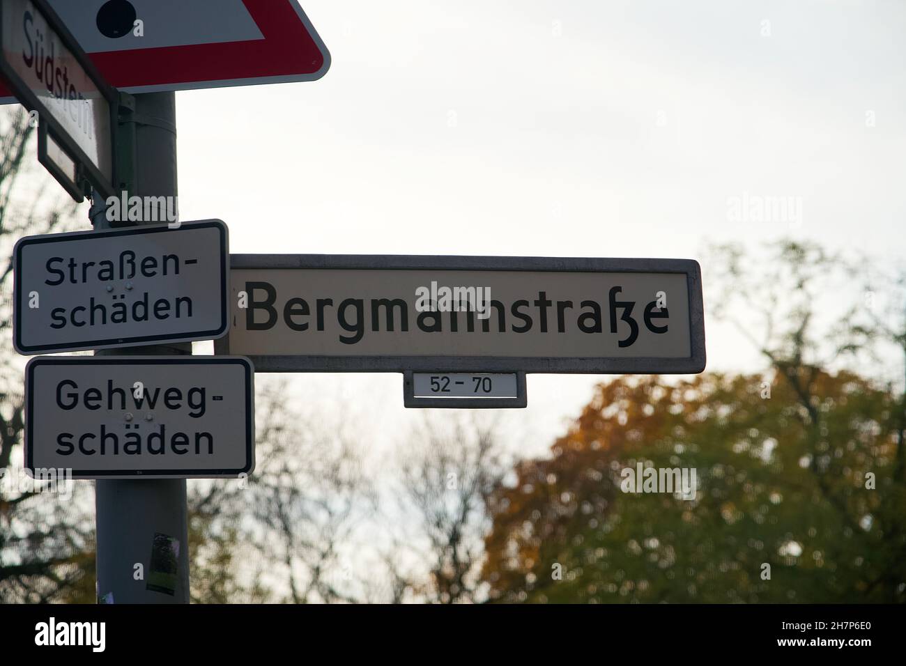 German Street Sign of Bergmannstrasse with additional Signs saying Roadway Damage and Sidewalk Damage Stock Photo