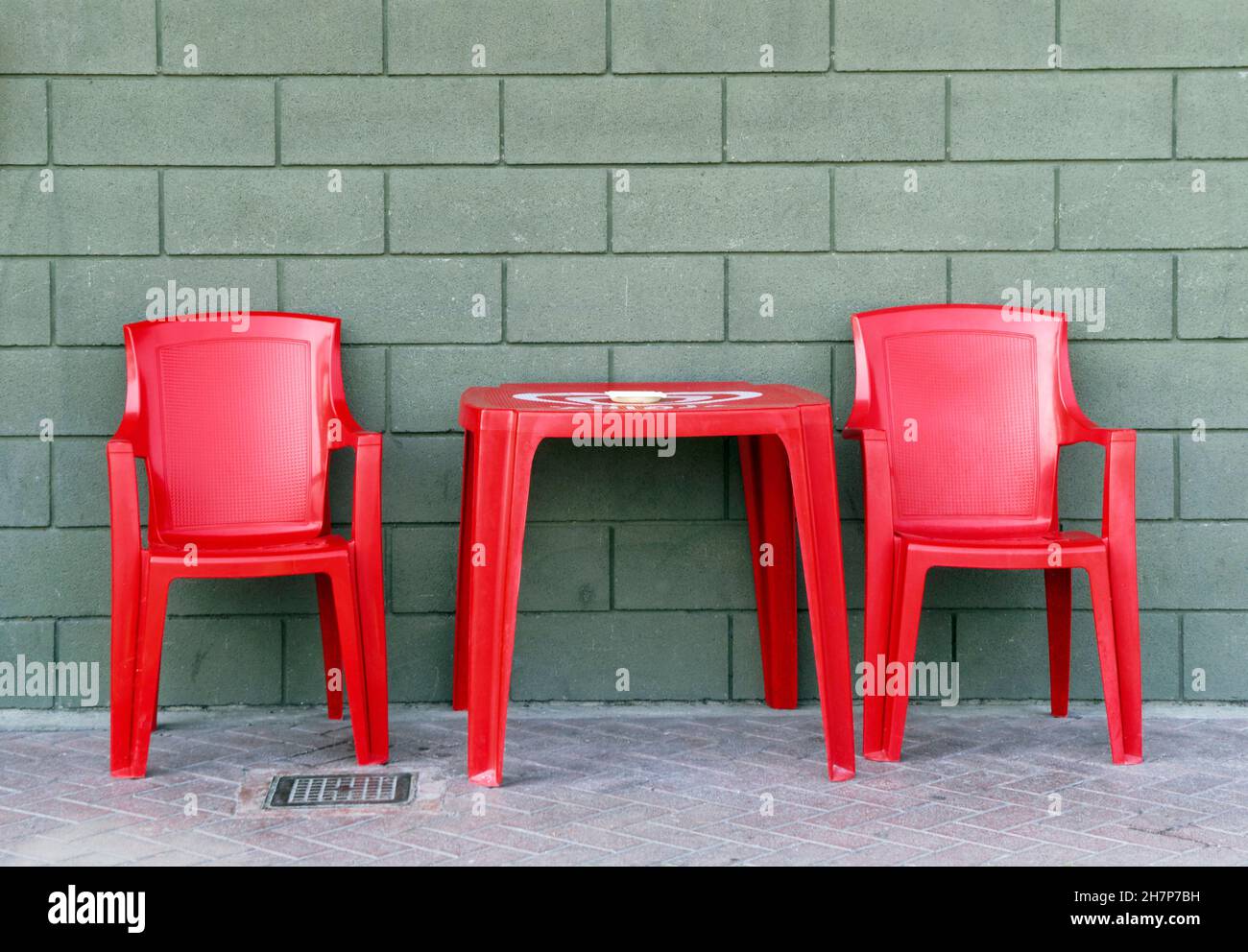 plastic red chairs and table against the wall of  a bar Stock Photo