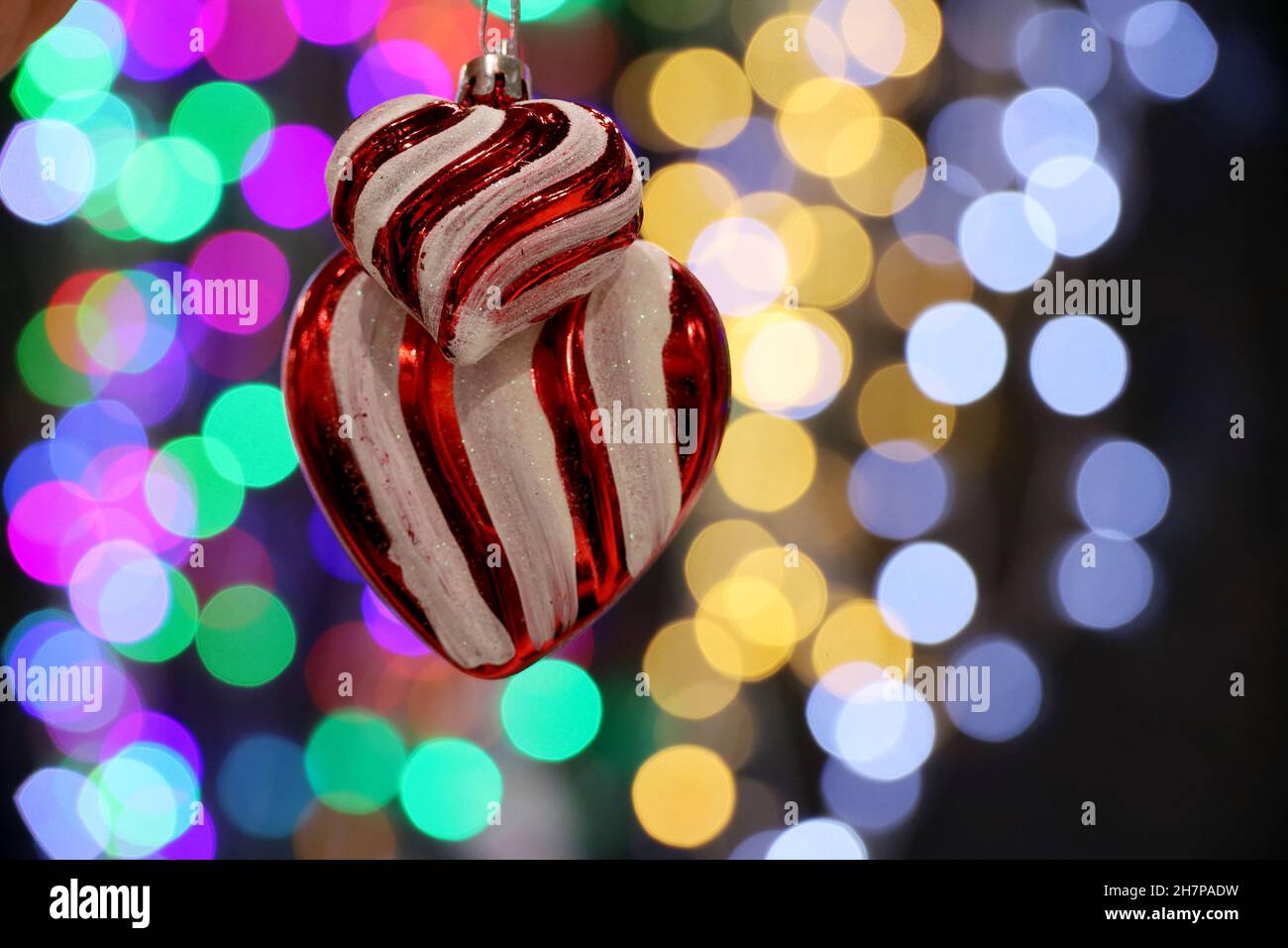Christmas toys in hearts shape on blurred lights background. New Year decorations and festive illumination Stock Photo