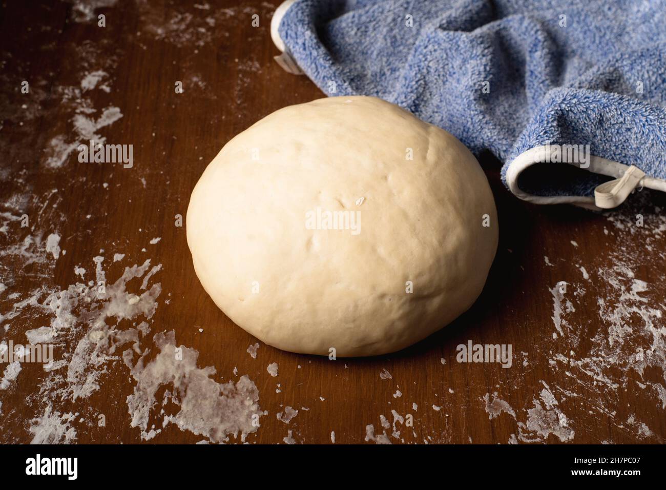 The finished kneaded round dough lies on the kitchen table at home ...