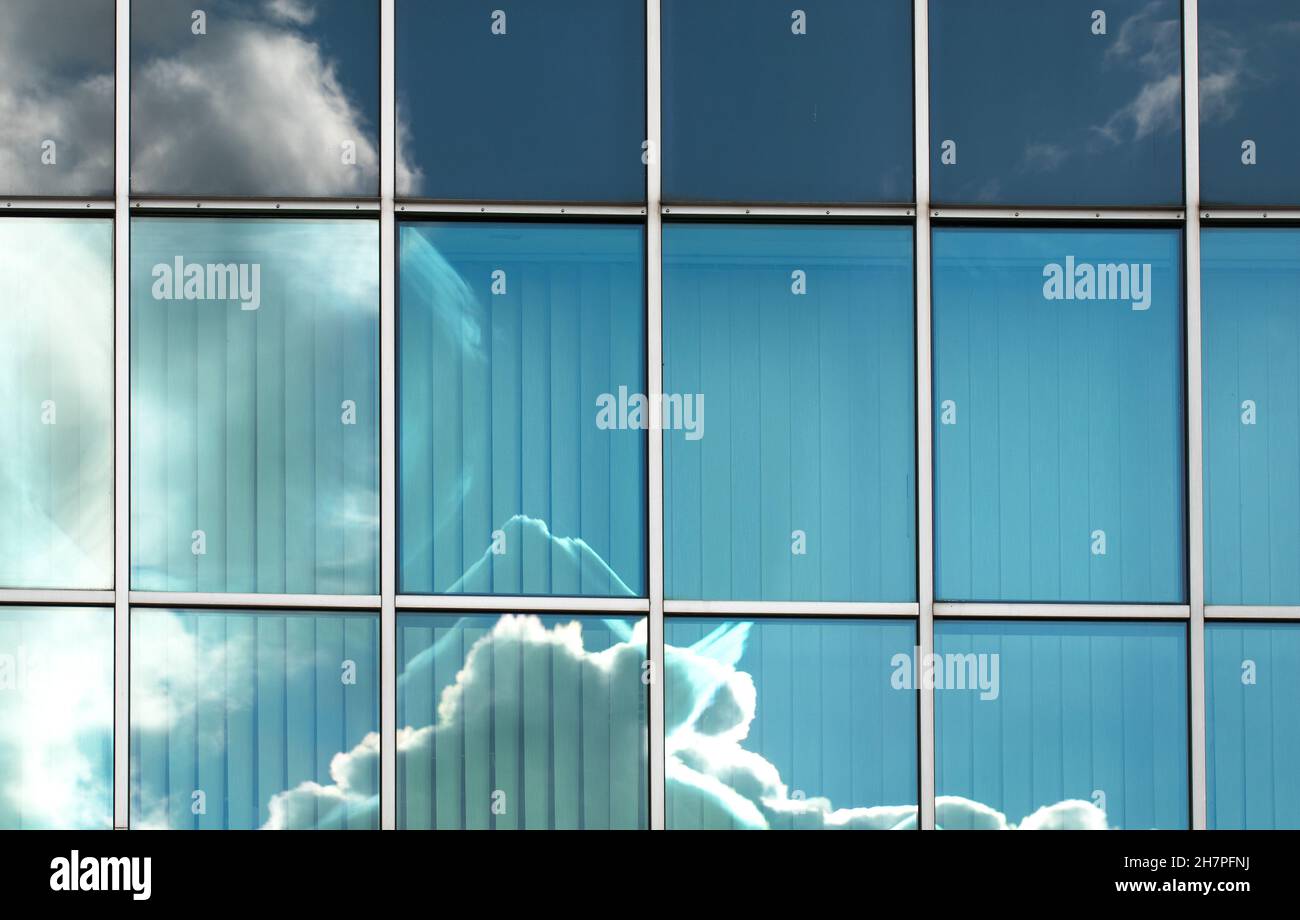 Reflection of clouds and blue sky in the glass structure of a ...