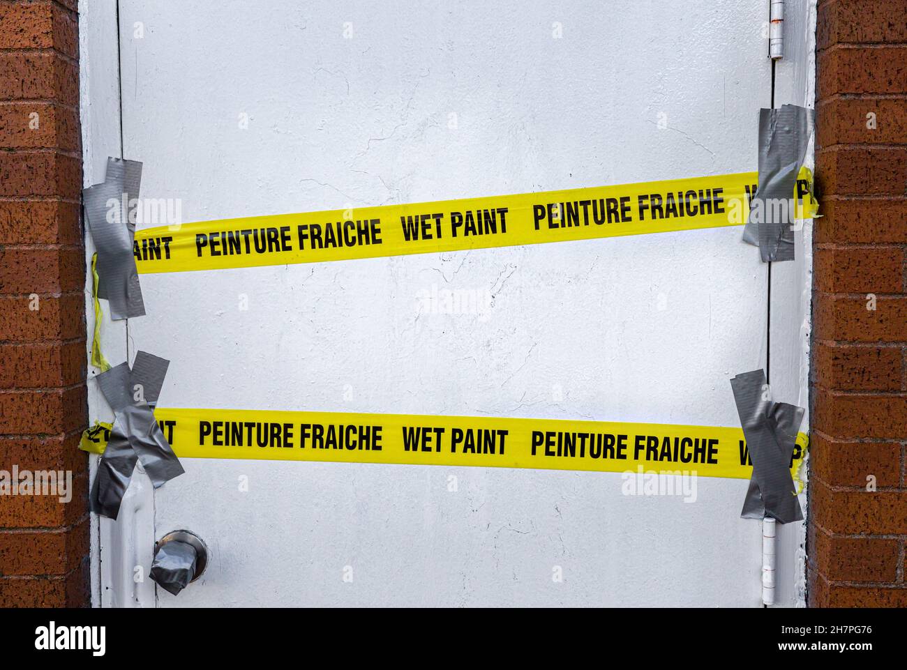 Yellow wet paint caution tape across a door. Wet paint caution tape