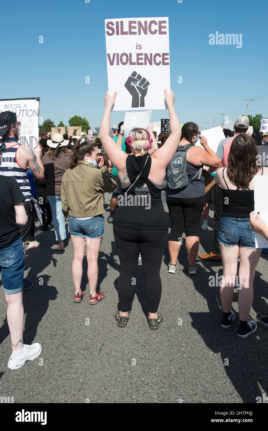 A woman stands in a crowd getting ready to march in a BLM protest holding a sign 'Silence Is Violence'  in Sterling Heights, Michigan on June 6, 2020. Stock Photo
