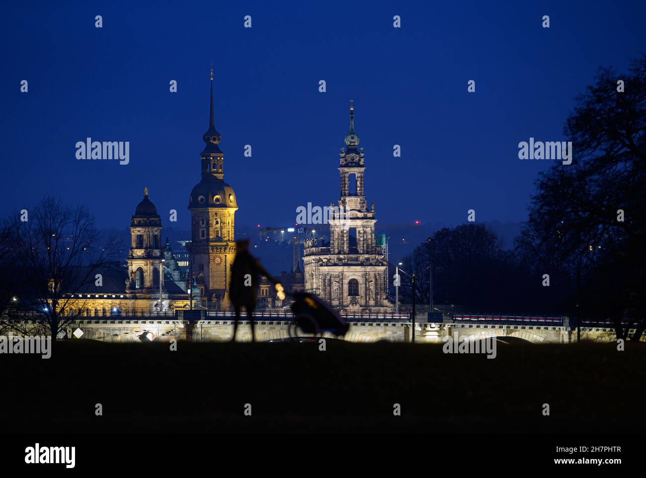 Dresden, Germany. 24th Nov, 2021. A woman with a baby carriage is standing on a path across the Elbe meadows in the Dresden district of Johannstadt in front of the old town backdrop with the Ständehaus (l-r), the Hausmannsturm and the Hofkirche. Credit: Robert Michael/dpa-Zentralbild/ZB/dpa/Alamy Live News Stock Photo