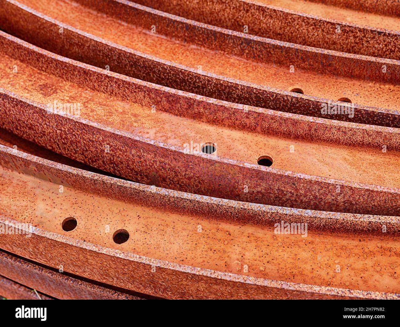 A set of steel rails has been stacked into concentric circles and then left outdoors to rust. Stock Photo