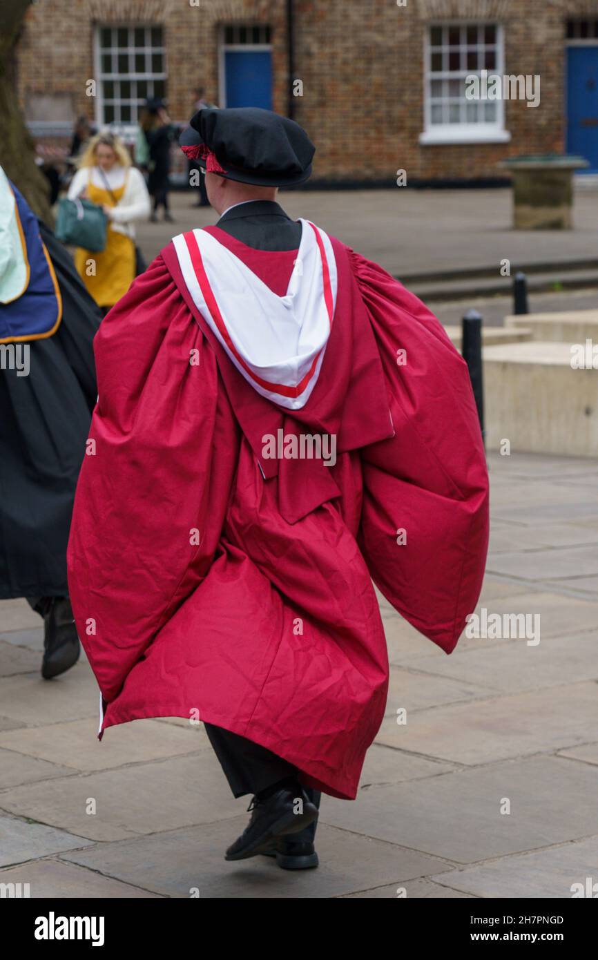 Graduate of St. John's University in a crimson gown makes his way through the streets of York, Minster for the ceremony., York, North Yorkshire, UK. Stock Photo