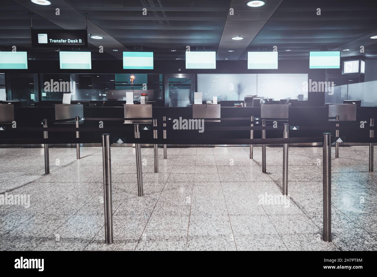 View of an airport check-in area with multiple empty decks for transfer passenger service and empty plasma TV screens on the top; chromium poles of po Stock Photo