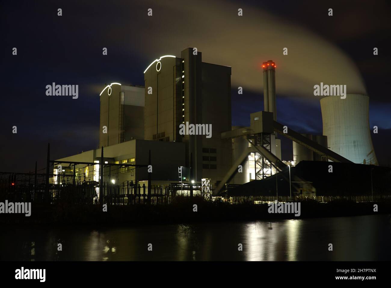 Coal-fired power plant with stone coal stockpile by night. Old technology that is one of the factors causing global warming. Hanover, Germany Stock Photo