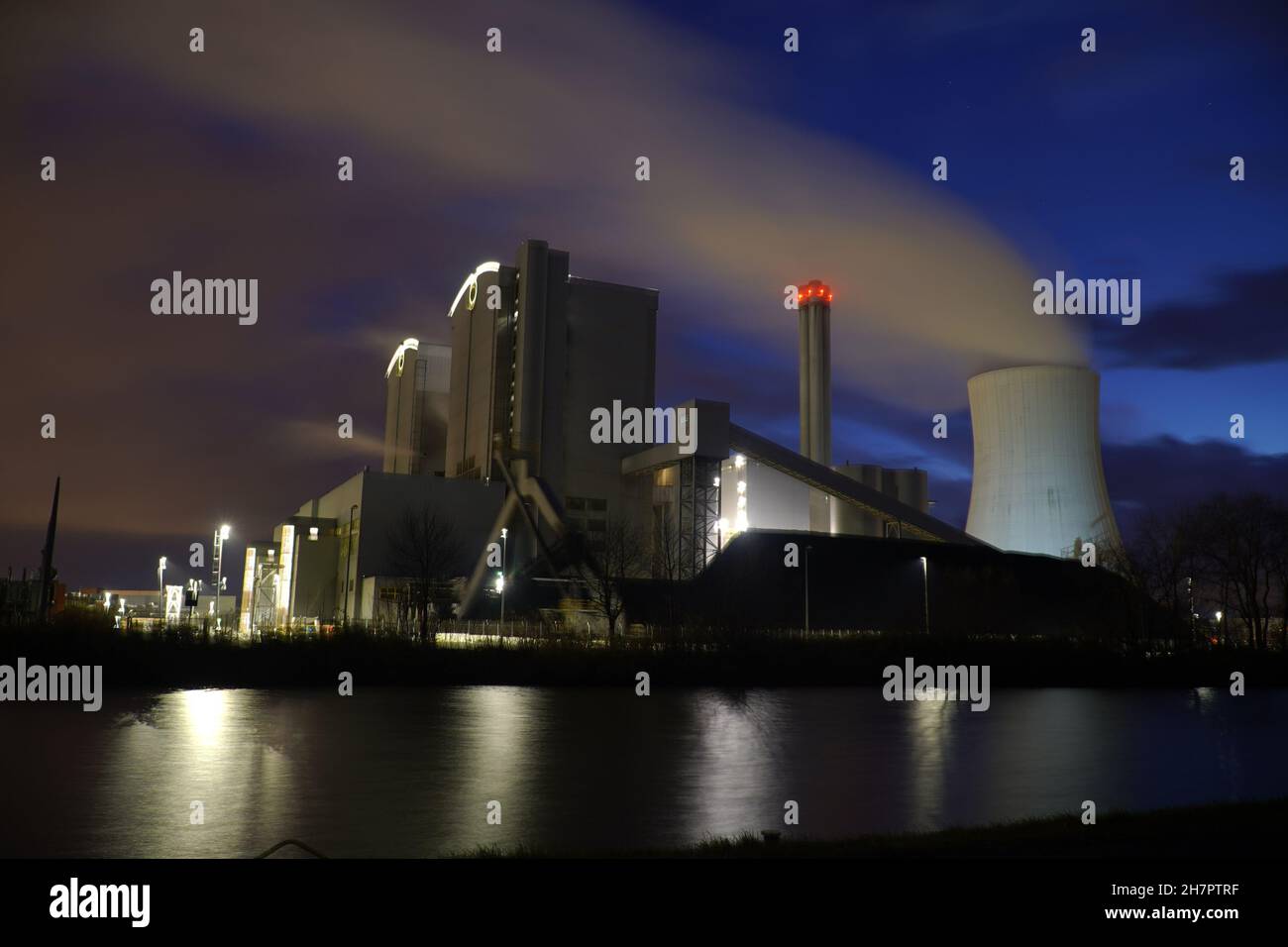 Coal-fired power plant with stone coal stockpile by night. Old technology that is one of the factors causing global warming. Hanover, Germany Stock Photo