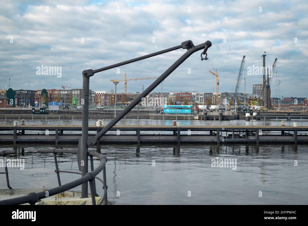 Building cranes in the Houthavens, a new residential area of Amsterdam with an old crane mounted on a converted barge in the foreground. Stock Photo