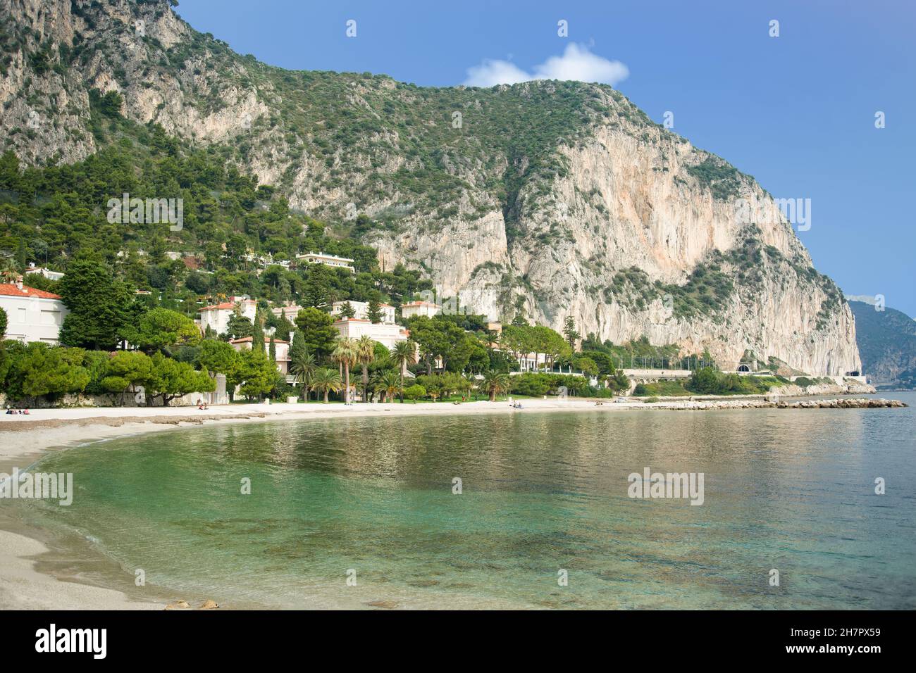'Petite Afrique' beach in Beaulieu sur mer on the French Riviera with luxury residences and limestone cliffs in the background. Stock Photo
