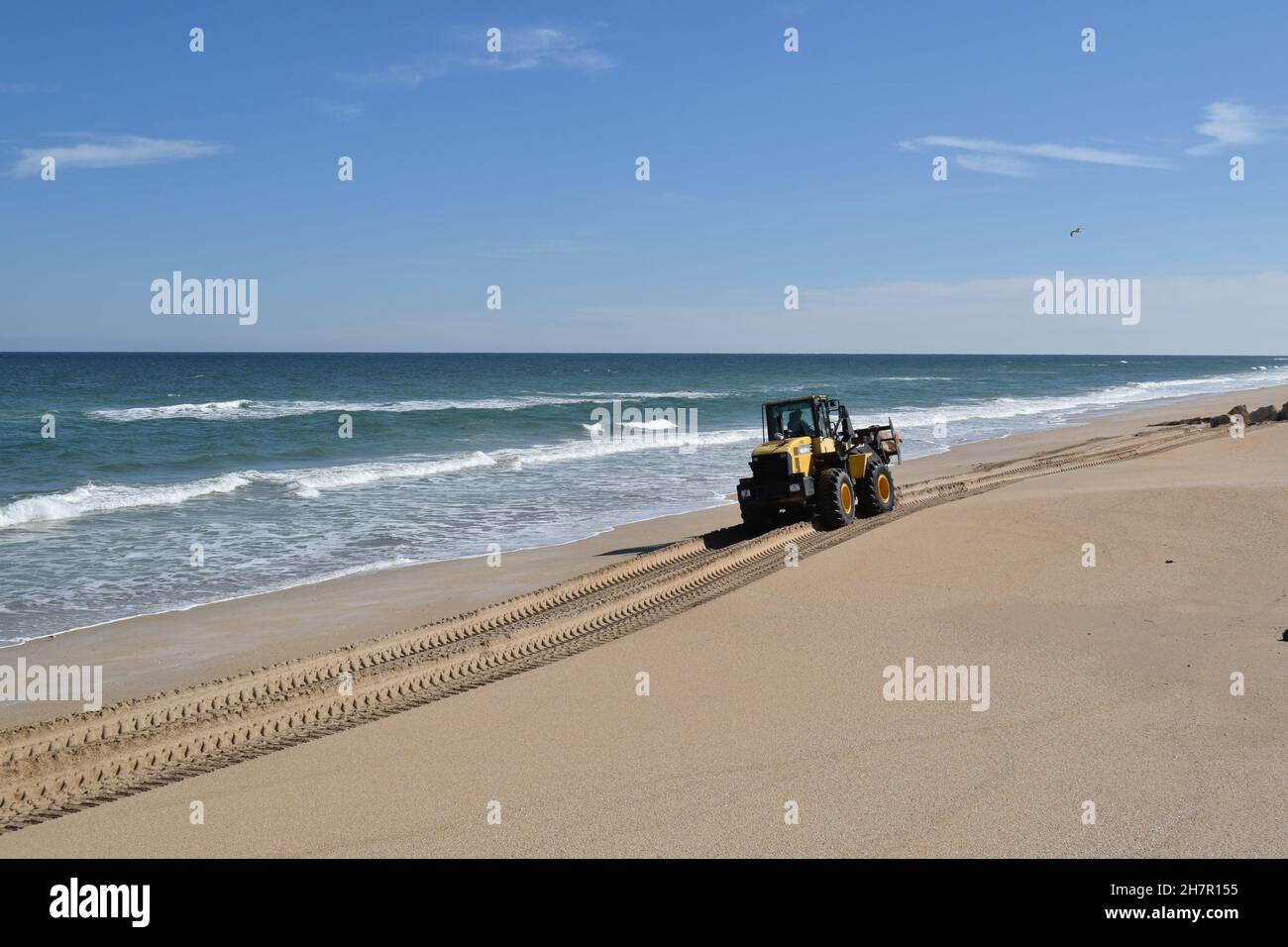 Heavy equipment moves a rock down the beach Stock Photo - Alamy