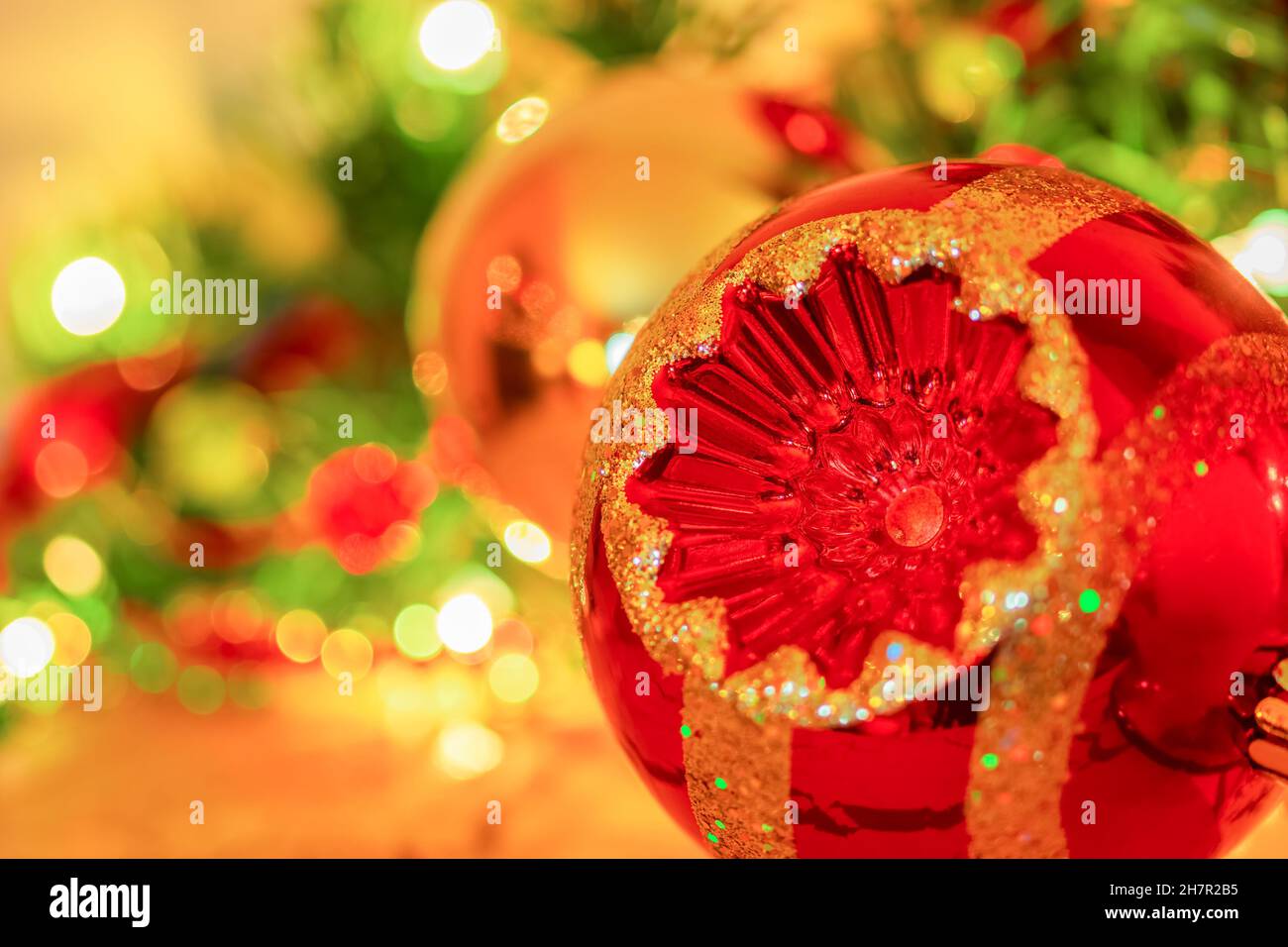 Christmas ornament in red and gold color is  surrounded by soft focus ornaments in bright glittering  colors on a fireplace mantel. Stock Photo