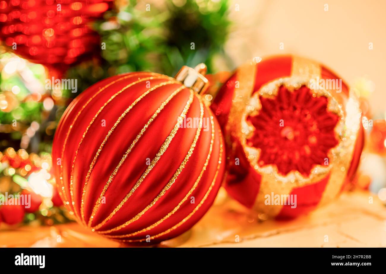 Christmas ornament in red and gold color in extreme close-up  is  surrounded by soft focus ornaments in bright glittering  colors on a fireplace mante Stock Photo