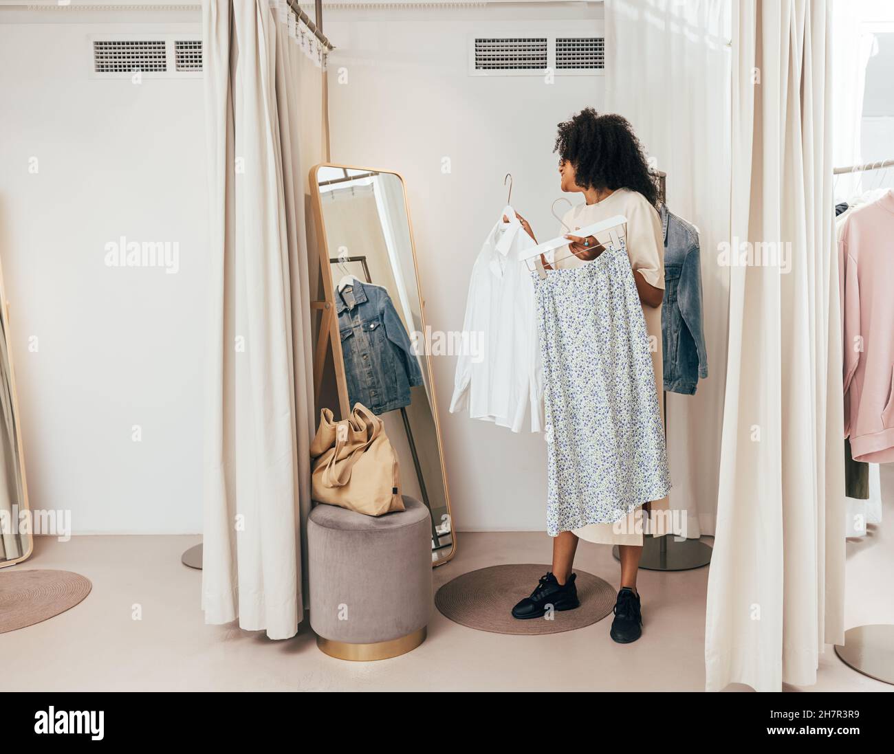 Young woman choosing clothes while standing in fitting room in a boutique Stock Photo